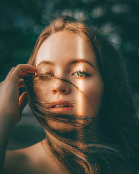 Retrato de una mujer con melena cobriza movida por el aire.